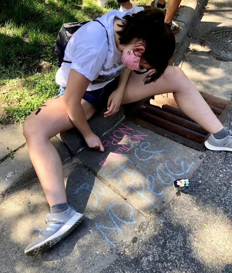 Senior Brianna Olson sitting, drawing with chalk 